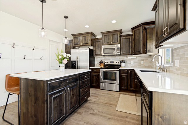 983 West 1550th Street South Springville, UT 84663 - Photo 19 of 43 Kitchen with wood-finish flooring, dark wood cabinetry, light-toned countertops, stainless steel appliances, and a tiled backsplash.