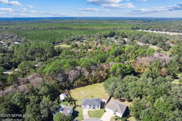 an aerial view of residential houses with outdoor space and trees