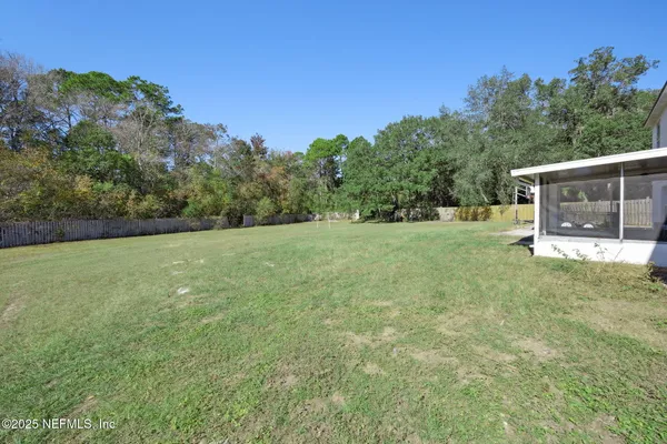 a view of a grassy field with trees in the background