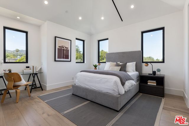 a bedroom with a bed a chair and painting on the wall