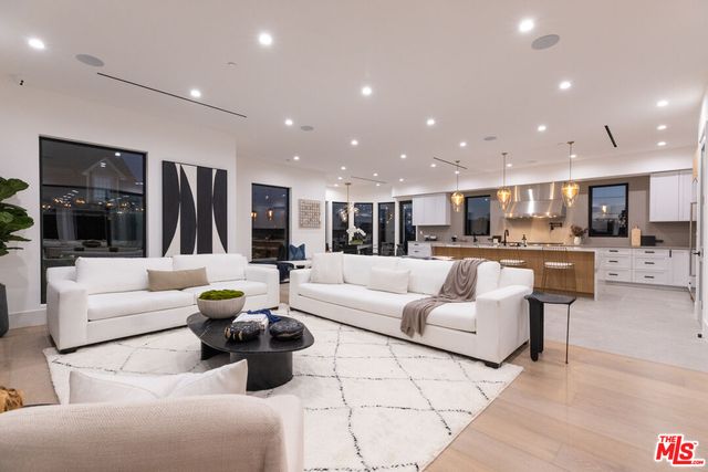 a living room with furniture kitchen view and a large window
