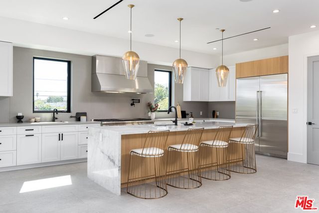 a large kitchen with a lot of white cabinets and stainless steel appliances