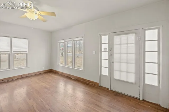 a view of an empty room with a window and wooden floor