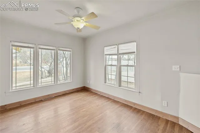 an empty room with chandelier fan and windows