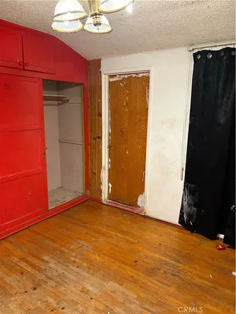 an empty room with wooden floor closet and windows