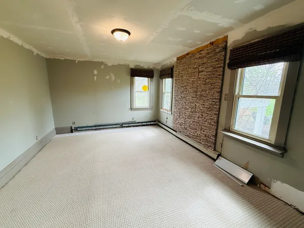 an empty room with wooden floor chandelier and windows