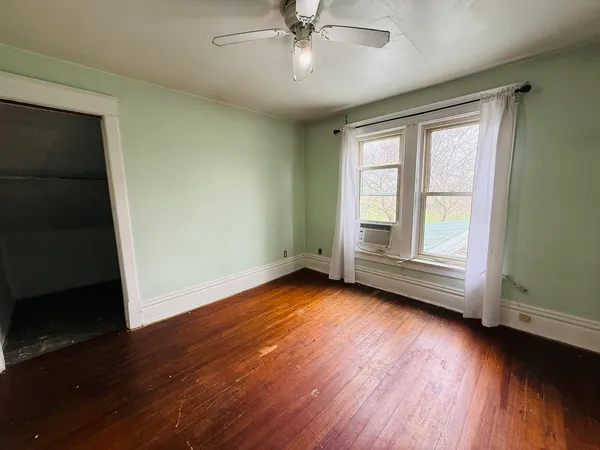 a view of a hallway with wooden floor and a bathroom