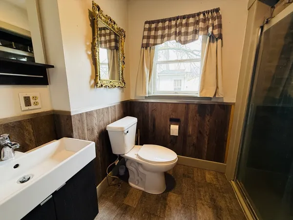 a bathroom with a sink a toilet a window and mirror