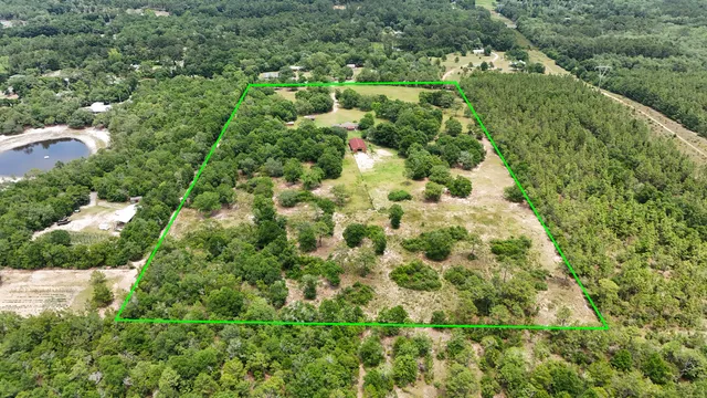 an aerial view of residential house with outdoor space and trees all around