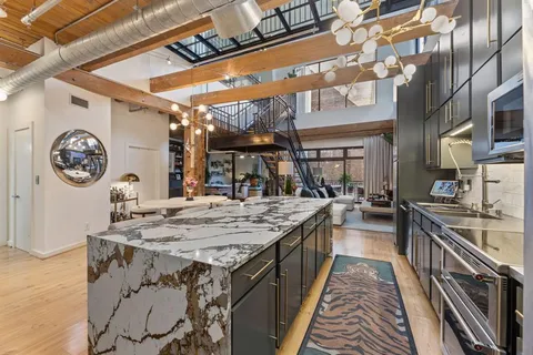 a dining hall with stainless steel appliances granite countertop a stove a kitchen island a dining table and chairs with the wooden floor