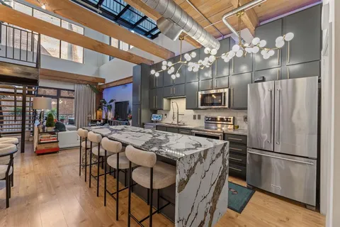 a kitchen with stainless steel appliances granite countertop a table chairs refrigerator and microwave