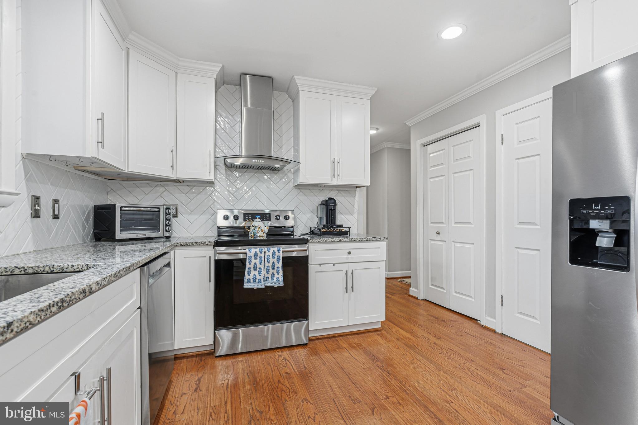 231 East Timonium Road Lutherville-Timonium, MD 21093 - Photo 26 of 66 a kitchen with stainless steel appliances granite countertop a stove top oven a sink and white cabinets with wooden floor