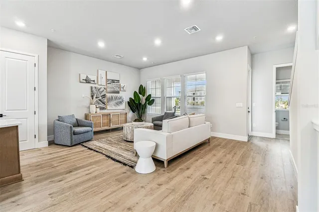 a living room with furniture kitchen view and a window