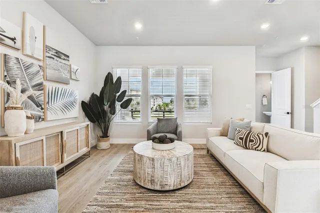a living room with furniture kitchen area and a wooden floor