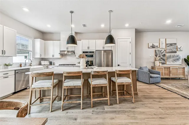 a kitchen with stainless steel appliances granite countertop a sink a stove and a wooden floors