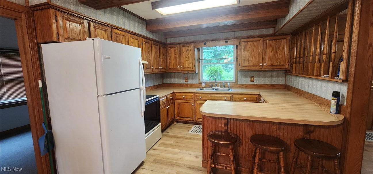 9090 Radcliffe Road Adamsville, OH 43802 - Photo 5 of 19 Kitchen with light hardwood / wood-style floors, kitchen peninsula, range with electric cooktop, white refrigerator, and sink