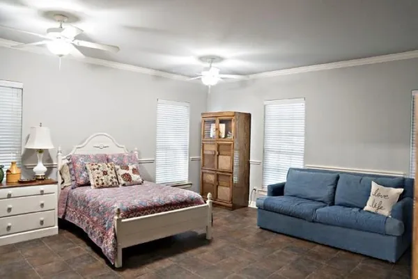 a bedroom with a large bed couch and a chandelier
