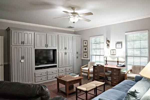 a living room with furniture a flat screen tv and floor to ceiling window
