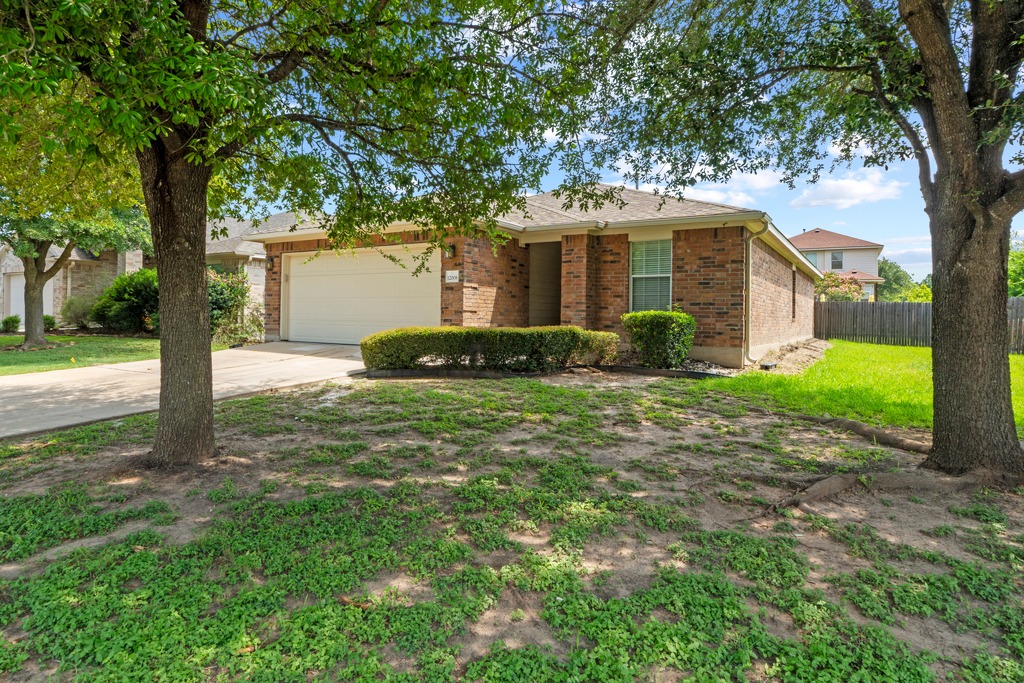 12008 Lansdowne Road Austin, TX 78754 - Photo 3 of 29 Mature trees shade this charming brick home, boasting a neatly landscaped front yard and attached garage.