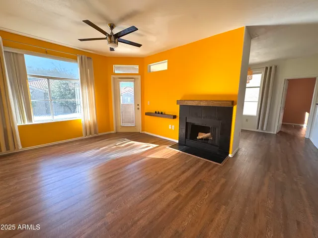 an empty room with wooden floor a fireplace and a window