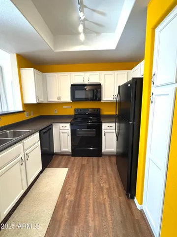 a kitchen with granite countertop a refrigerator a sink dishwasher and wooden cabinets