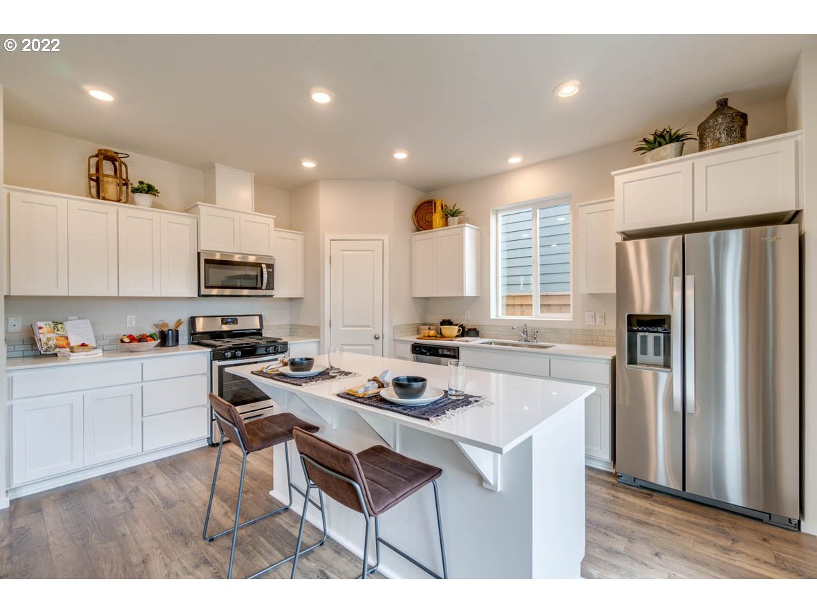 2949 V Street Springfield, OR 97477 - Photo 14 of 31 a kitchen with stainless steel appliances granite countertop a refrigerator a stove a sink dishwasher a dining table and chairs with wooden floor