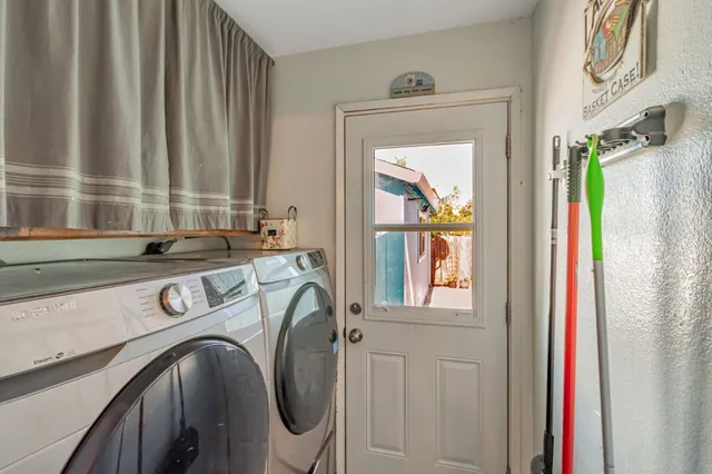 a utility room with stainless steel appliances granite countertop a sink and a window