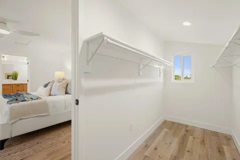 a view of a bedroom with wooden floor and a ceiling fan