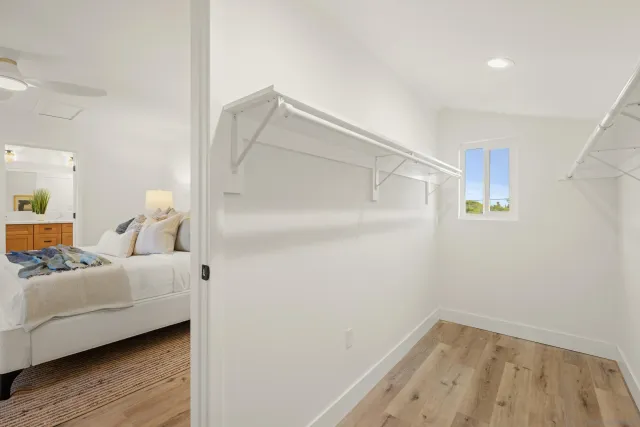a view of a bedroom with wooden floor and a ceiling fan