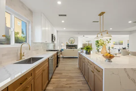 a view of a kitchen with kitchen island a large counter top space a sink stainless steel appliances and windows