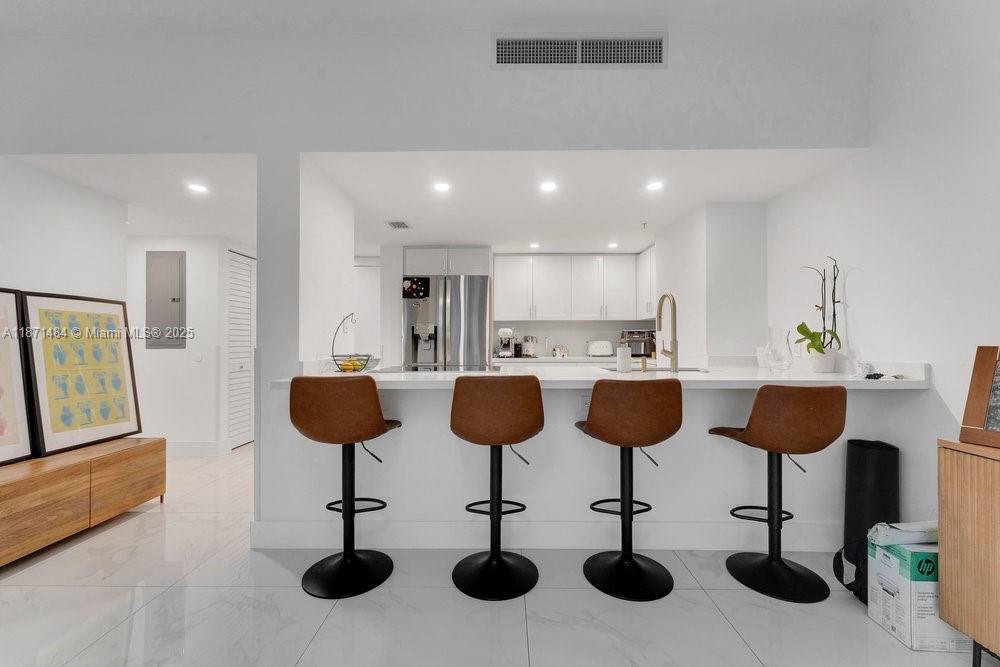 1800 North Bayshore Drive, Unit 614 Miami, FL 33132 - Photo 4 of 29 a kitchen with stainless steel appliances kitchen island granite countertop wooden cabinets and chairs