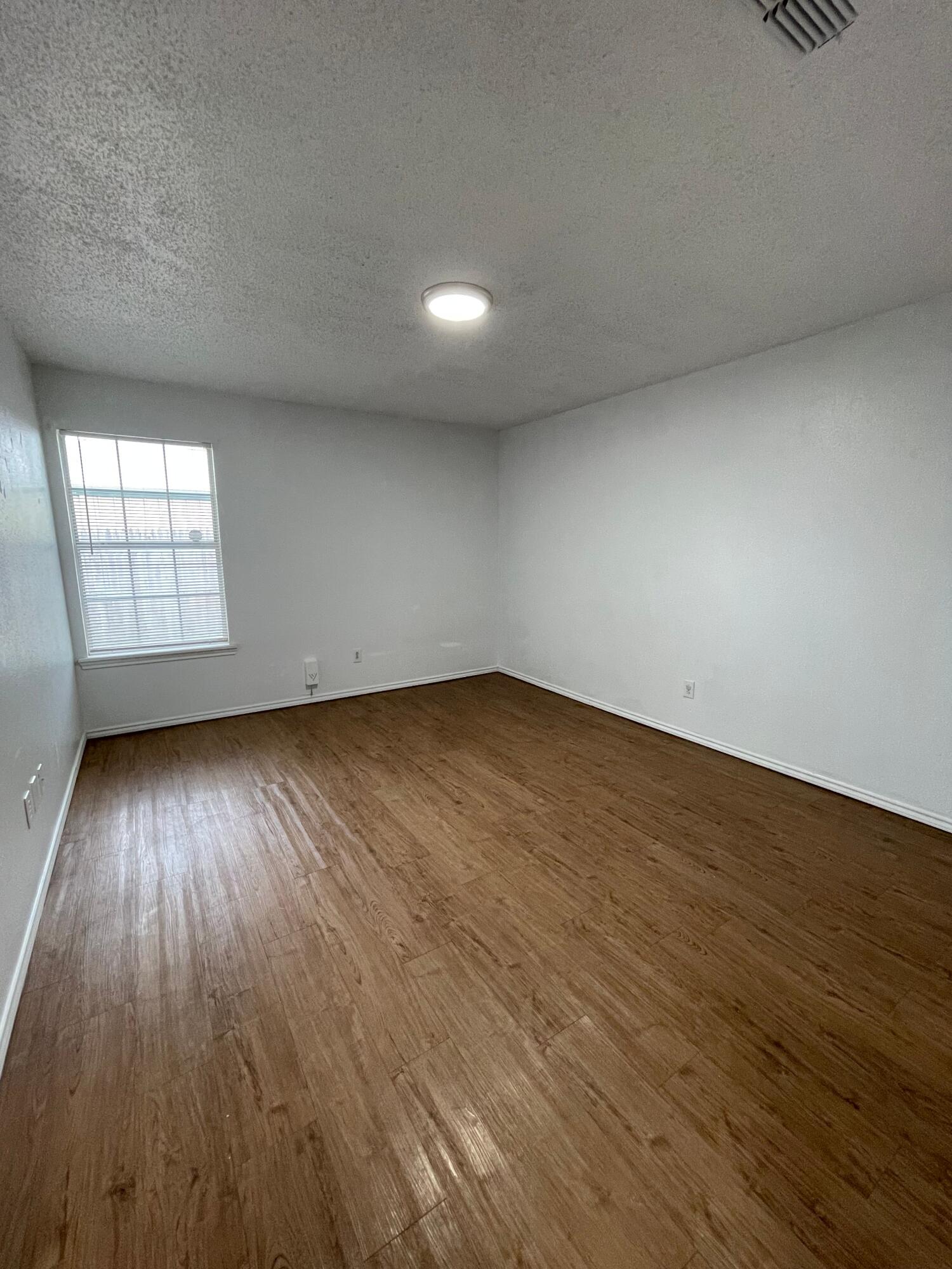 2344 78th Street Lubbock, TX 79423 - Photo 11 of 13 an empty room with wooden floor and windows