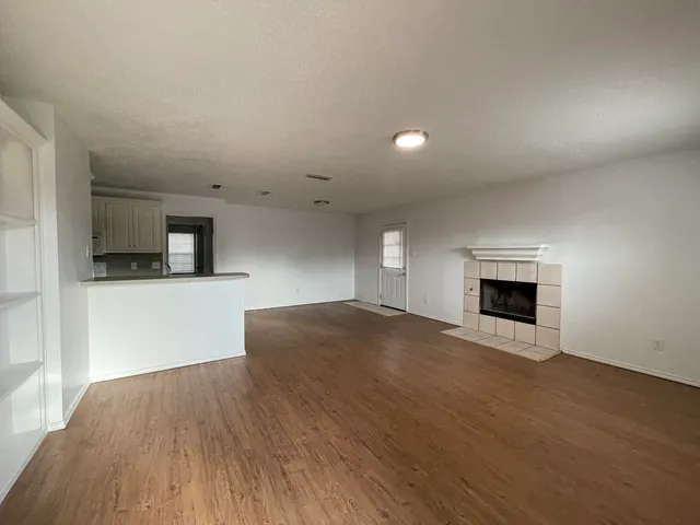 a view of empty room with wooden floor and fireplace