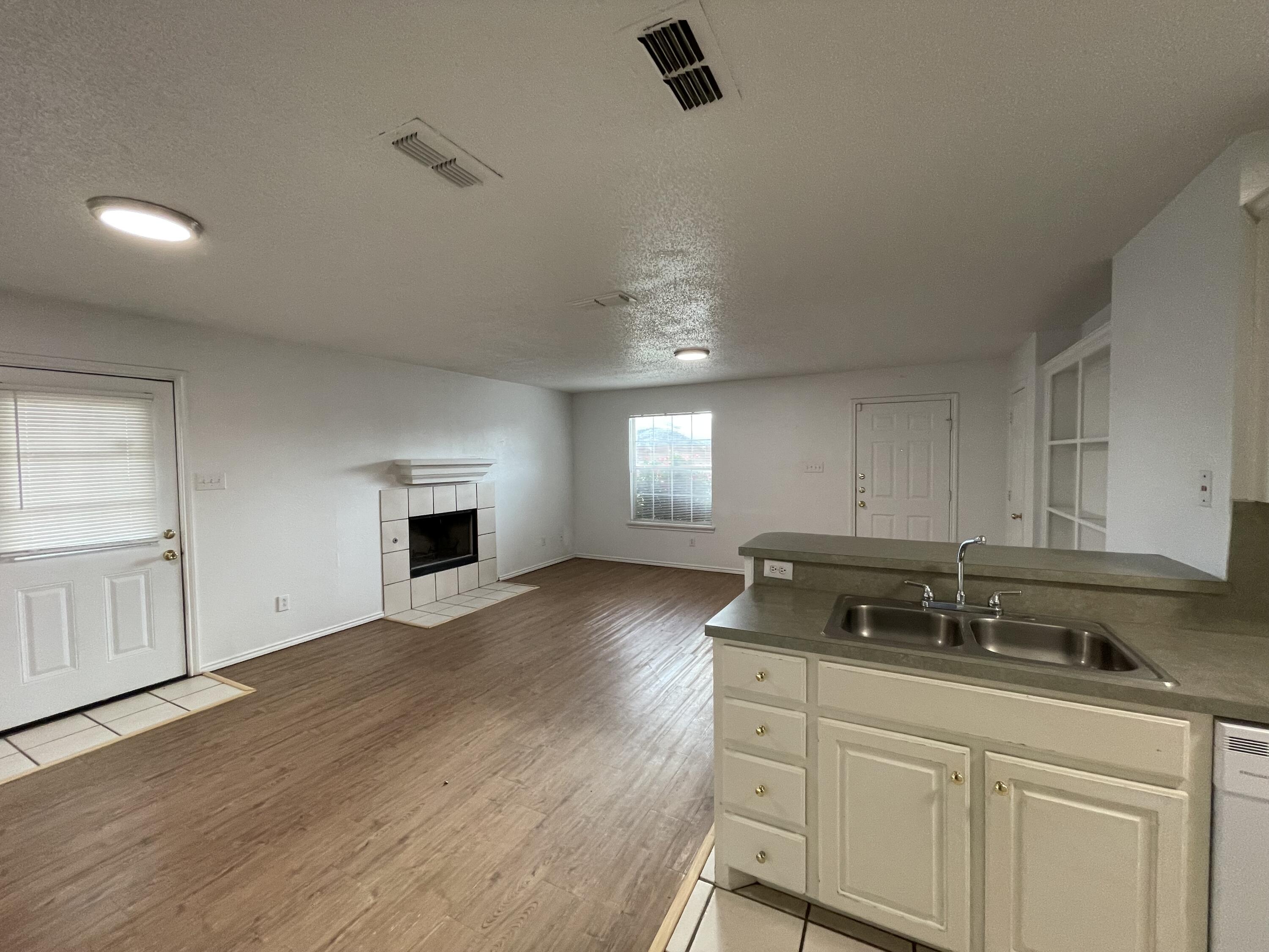 2344 78th Street Lubbock, TX 79423 - Photo 4 of 13 a kitchen with granite countertop a stove a sink and white cabinets with wooden floor