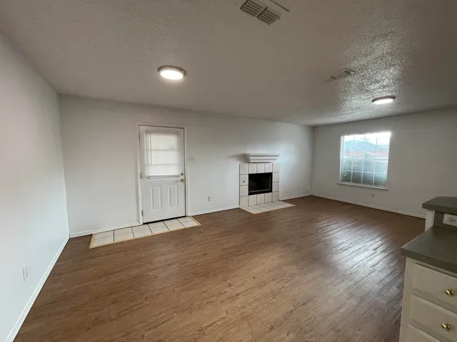an empty room with windows and fireplace