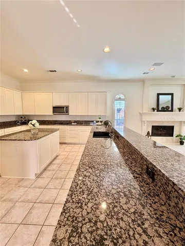 a large kitchen with kitchen island granite countertop a stove a sink a counter top space and cabinets