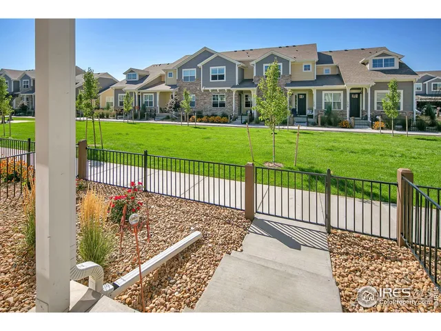 a view of a white house with a big yard plants and large trees