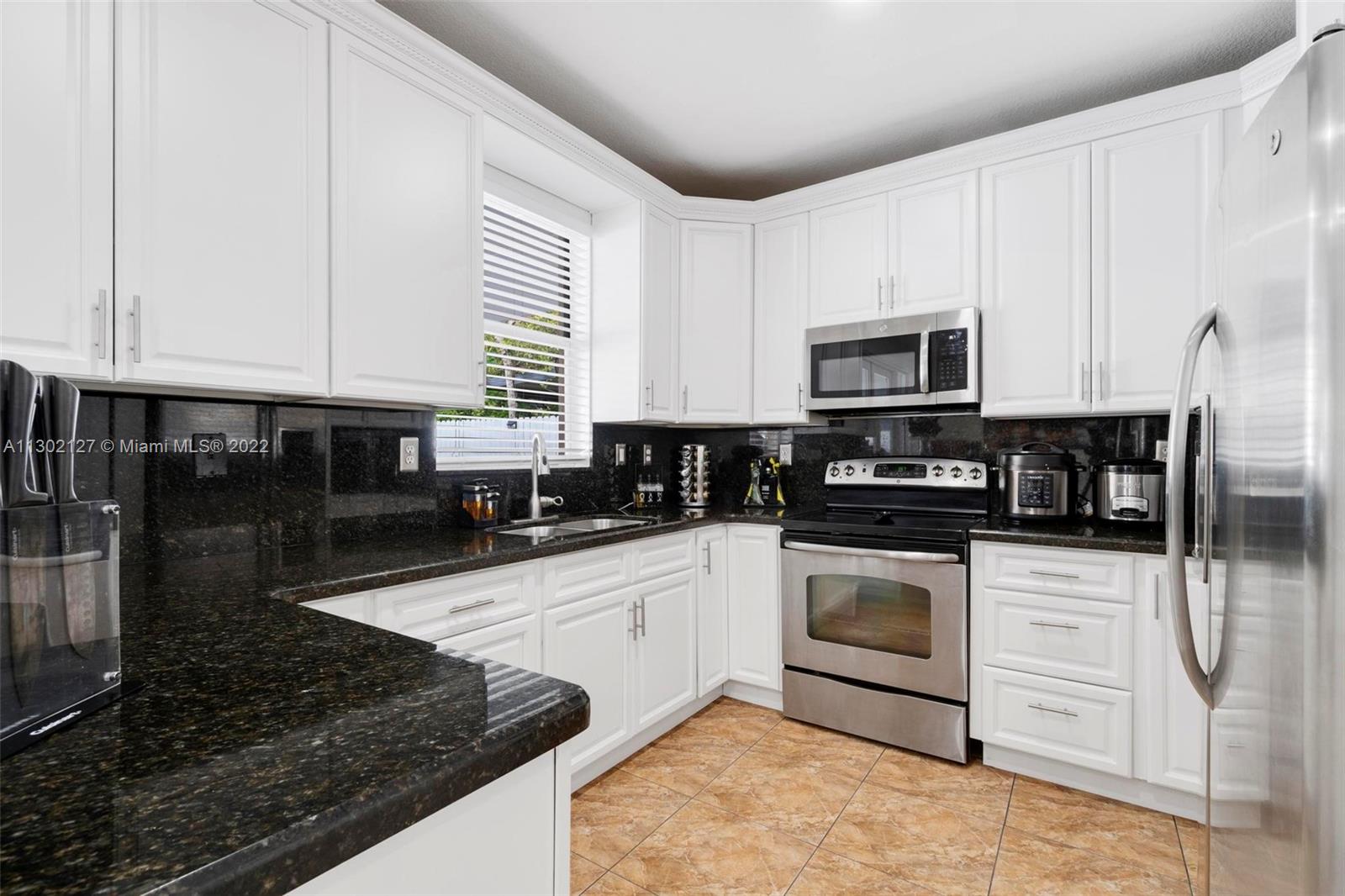 10837 Southwest 246th Street Homestead, FL 33032 - Photo 12 of 44 a kitchen with stainless steel appliances granite countertop a stove a sink and a microwave