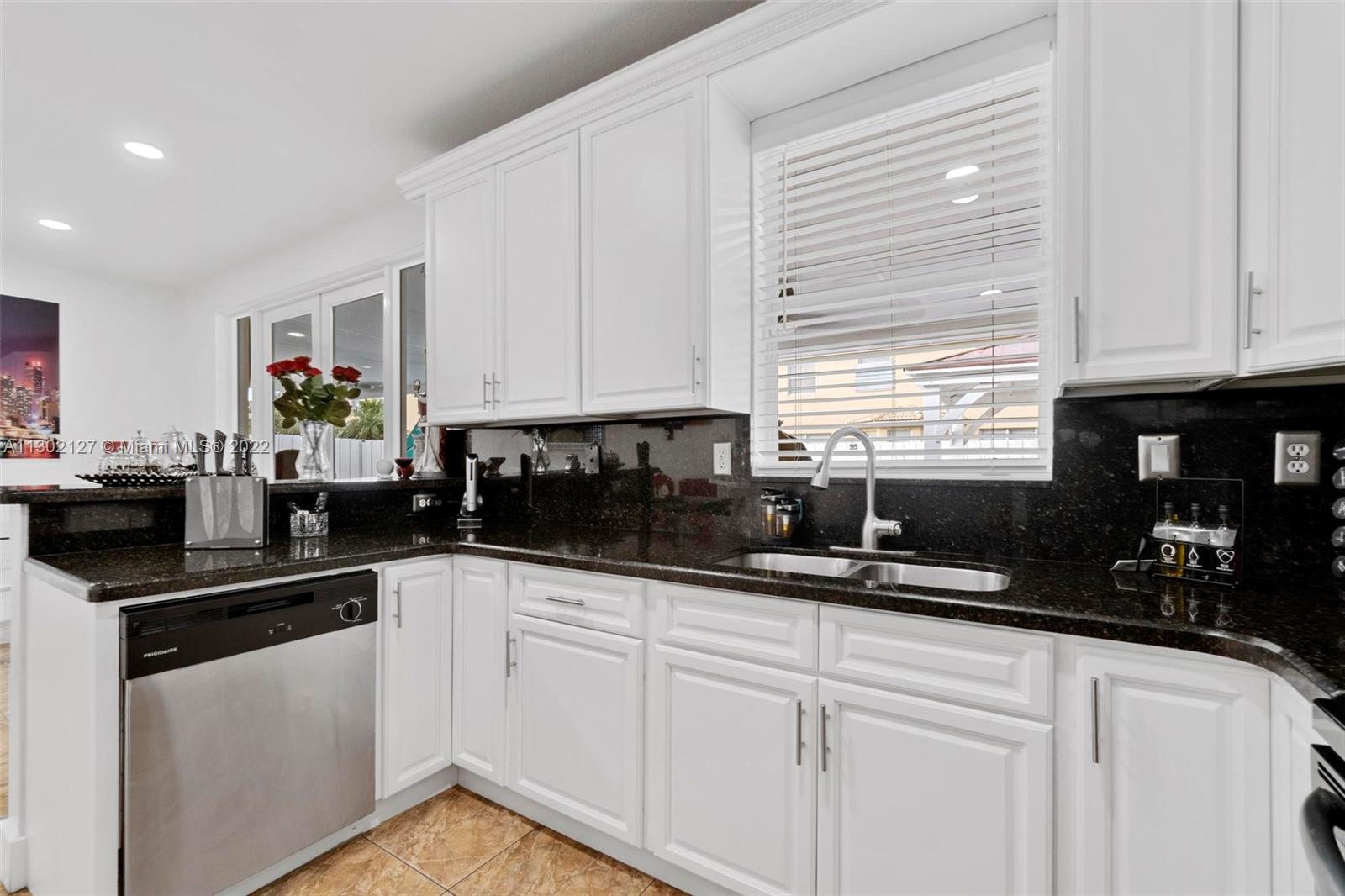 10837 Southwest 246th Street Homestead, FL 33032 - Photo 13 of 44 a kitchen with granite countertop a sink stainless steel appliances and white cabinets