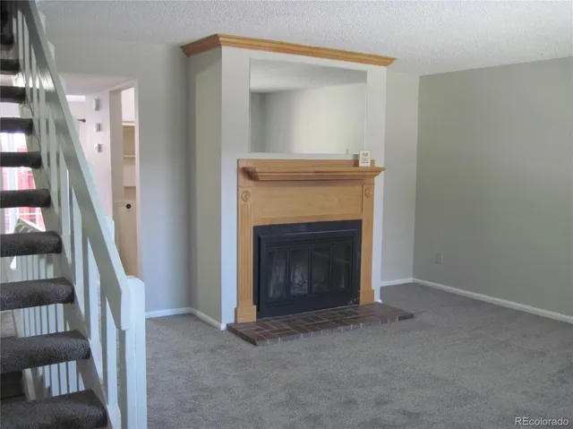 a view of an empty room with stairs and a fireplace