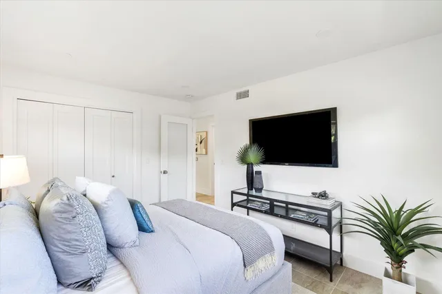a spacious bedroom with a bed and a flat screen tv
