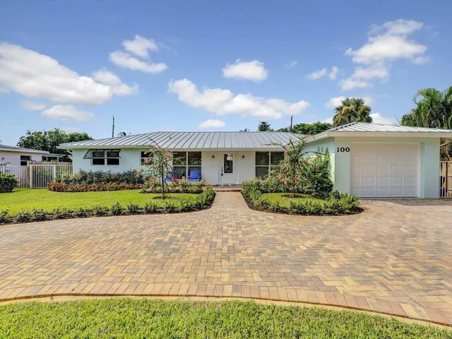 a view of a white house with a yard and potted plants