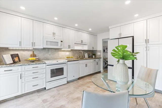 a kitchen with stainless steel appliances kitchen island granite countertop a white cabinets a stove a sink and a white wooden cabinets