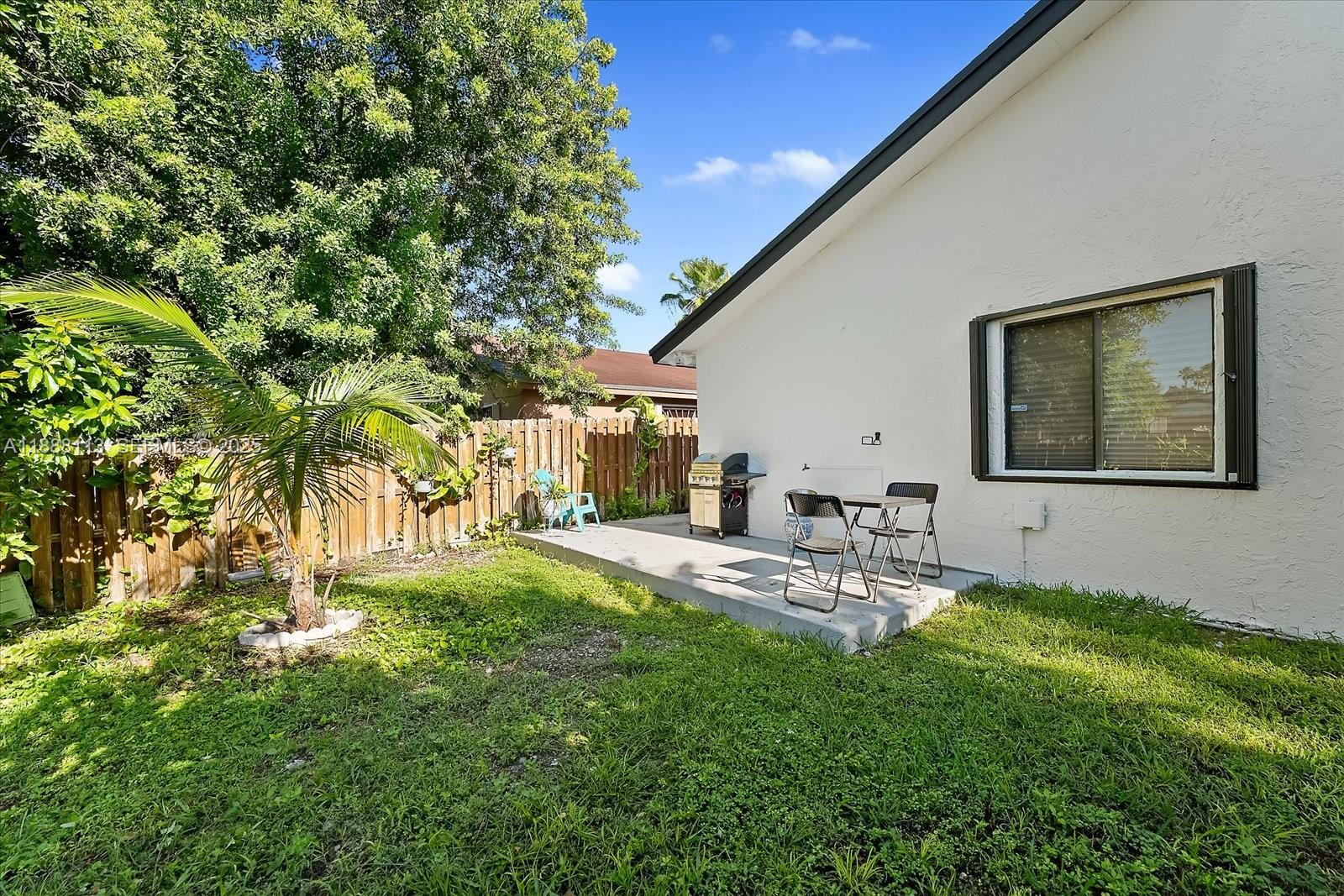 13556 Southwest 285th Terrace Homestead, FL 33033 - Photo 23 of 25 a view of a patio with table and chairs and potted plants with wooden fence