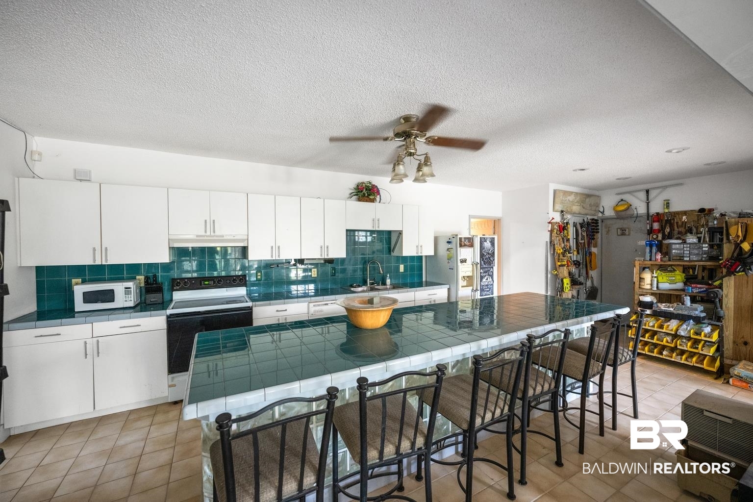 29255 Ono Boulevard Orange Beach, AL 36561 - Photo 39 of 43 Kitchen featuring range with electric stovetop, white microwave, tile counters, under cabinet range hood, and freestanding refrigerator