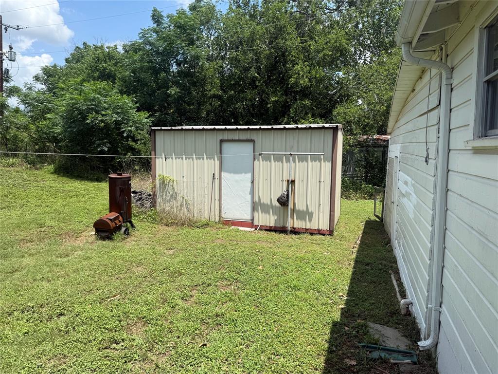 1825 East Pierce Street Luling, TX 78648 - Photo 13 of 16 An accommodating storage shed provides practical utility in the backyard.