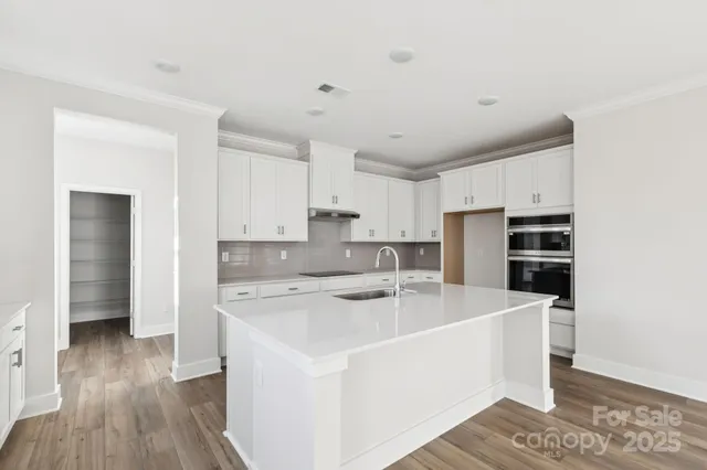 a kitchen with a sink a stove a refrigerator and white cabinets