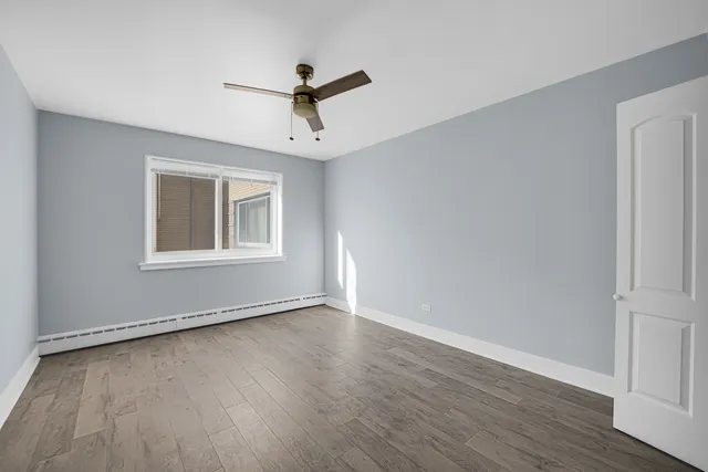a view of empty room with wooden floor and fan