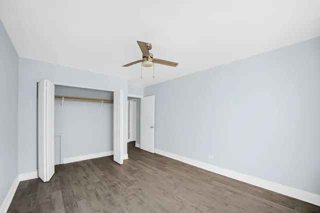 an empty room with wooden floor and ceiling fan