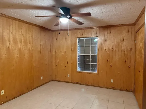 an empty room with windows and ceiling fan